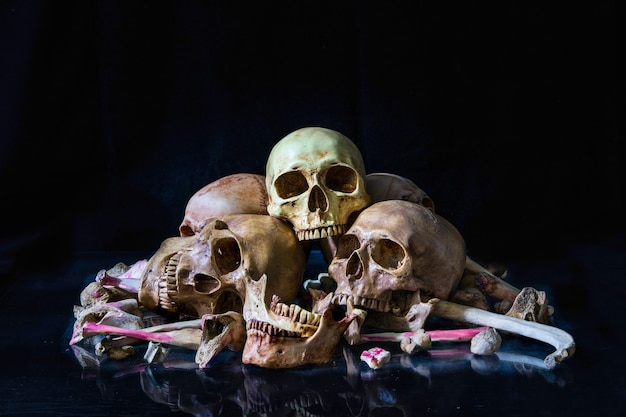 暗い背景に人間の頭蓋骨や骨の山。ハロウィーンのコンセプト