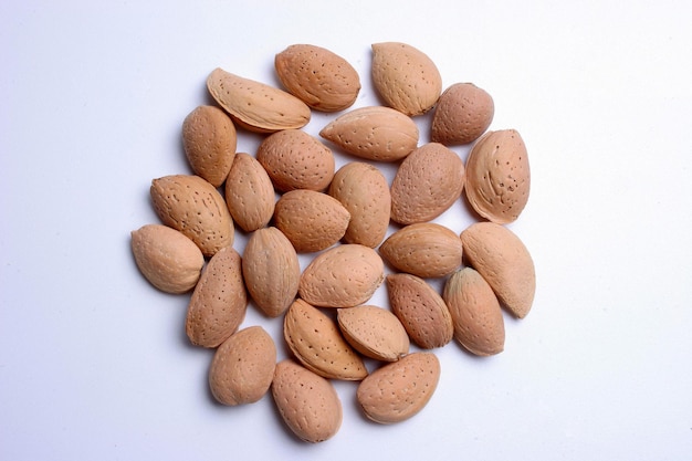 A pile of inshell almonds on a white background