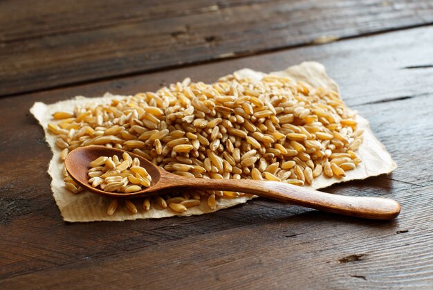 Pile of Kamut grain on wooden table with a spoon