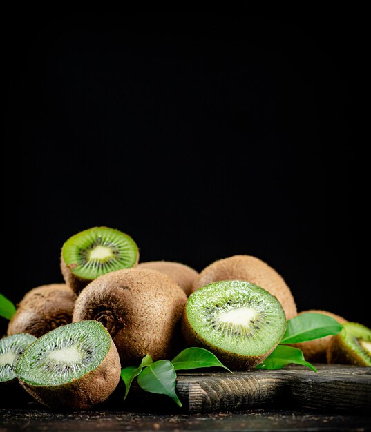 Foto un mucchio di kiwi con foglie su un tagliere