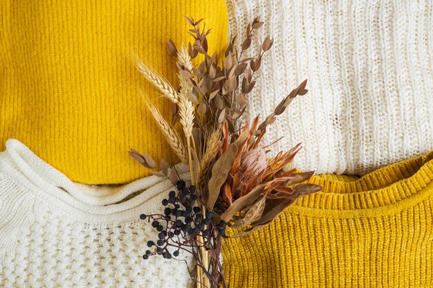 Pile of knitted clothes with dried flower bouquet