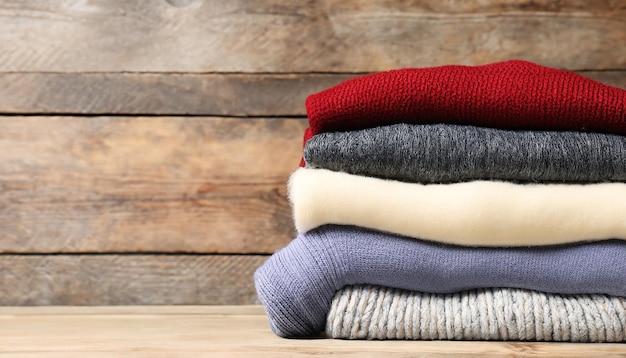 木製の背景のセーターに編んだ冬の服の山 編み物のテキストスペース