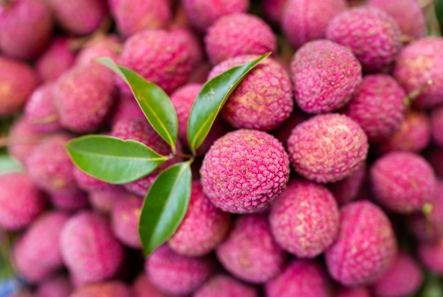 A pile of lychee fruit with a green leaf.