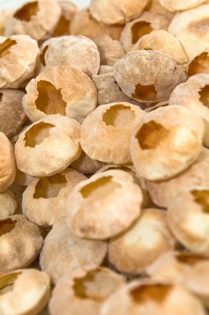 A pile of macadamia nuts with holes in the middle.