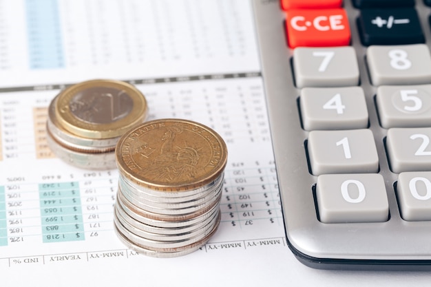 Pile of money coins with graph paper on wood table, concept in account, finance and growth of business 