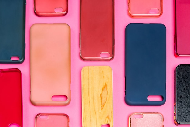 Foto mucchio di cover posteriori in plastica multicolore per telefono cellulare. scelta di accessori di protezione per smartphone su sfondo rosa. un sacco di dorsi o pelli di telefono in silicone uno accanto all'altro