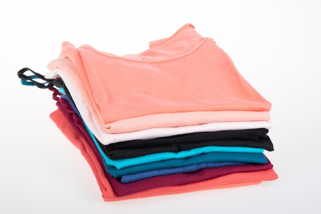 Pile of multicolored tank tops t shirt fabric cotton tshirts\
pile of various colored shirts on white table background