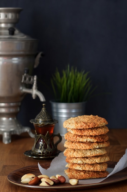 Pile Oatmeal Cookies with nuts and black tea at Samovar on a wooden table