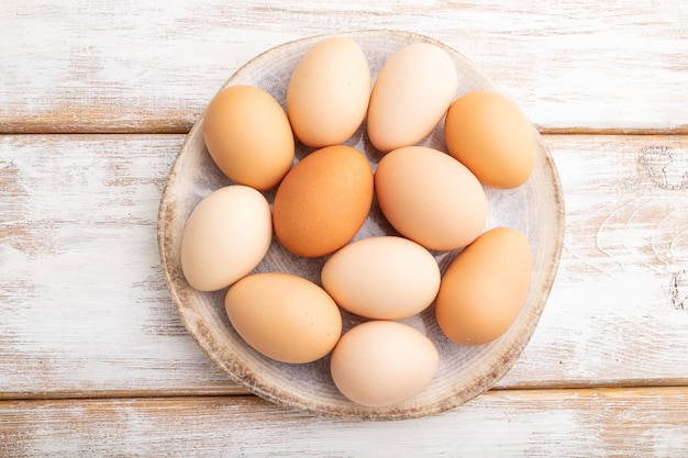 Фото Куча крашеных яиц на тарелке на белом деревянном фоне вид сверху крупным планом