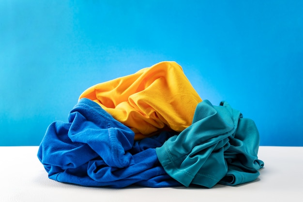 Фото Куча грязной прачечной одежды на белом столе синий фон.