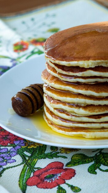 写真 新鮮に焼いたパンケーキと蜂蜜を皿に並べて朝食と自家製の食事のコンセプト