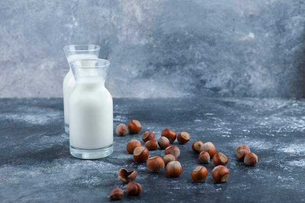 Pile of organic shelled hazelnuts with glasses of fresh milk.