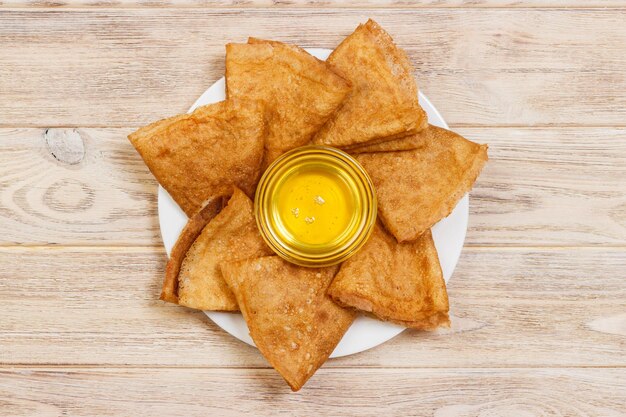 A pile of pancakes honey for the celebration of the carnival Thin pancakes for breakfast Pancakes and honey Maslenitsa Pancakes with honey on a white wooden background space for text