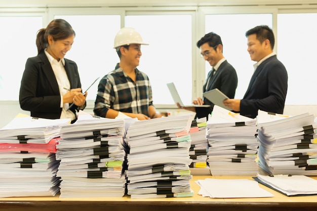 立っている幸せなビジネス人々のグループとテーブルの上の書類の山。