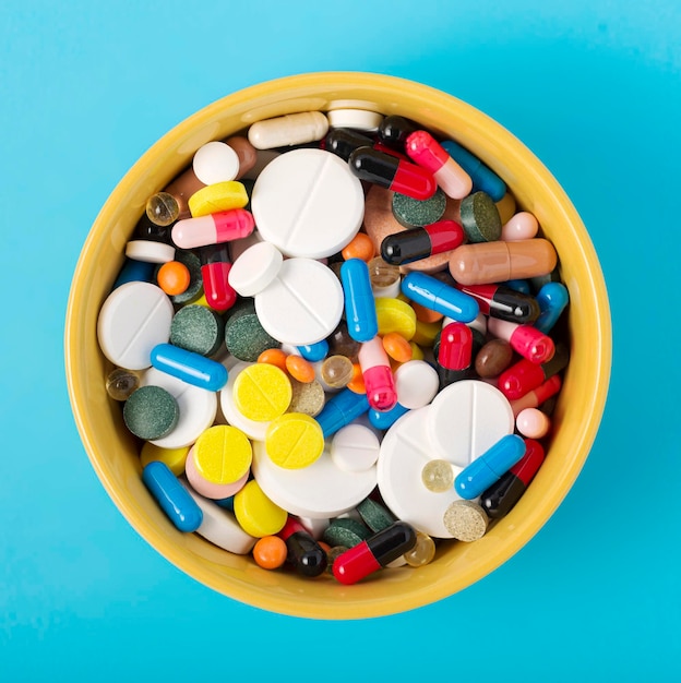Pile of pills in a bowl on a blue background