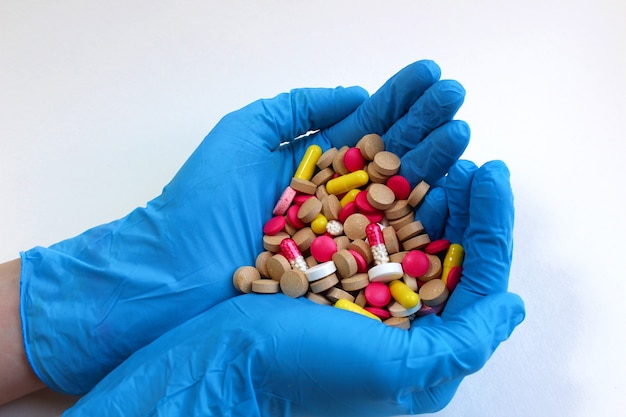 A pile of pills in the palms of a female hand in gloves A handful of medicines to treat various diseases