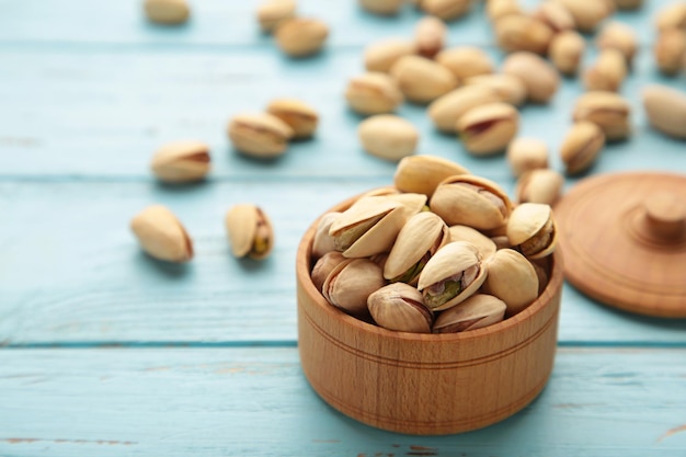 Pile of Pistachios on wooden bowl pistachios on blue wooden background