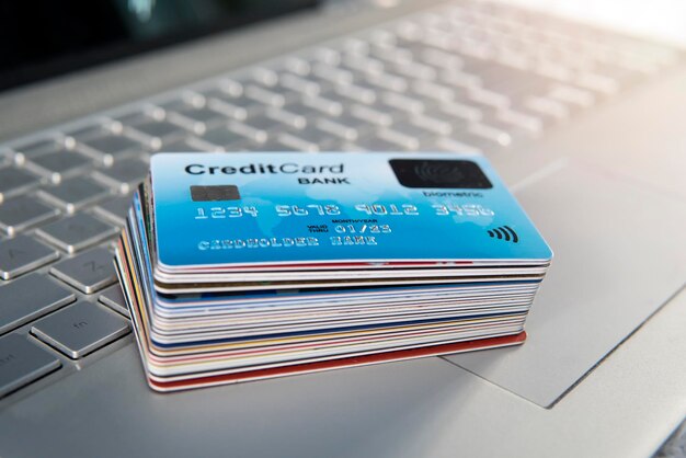 Photo pile of plastic credit cards on the laptop keyboard. open access for online shopping using biometric card. payment cards with finger sensor on the surface. payment system of new generation. stack.