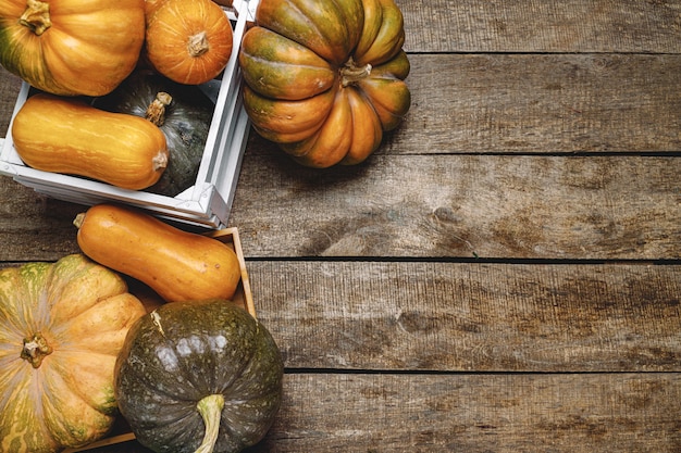 Pile of pumpkins in wooden box on old wooden board