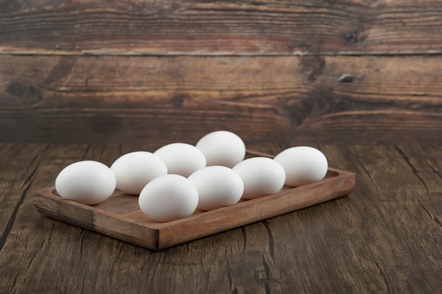 Mucchio di uova bianche fresche crude sul piatto di legno. Foto Premium