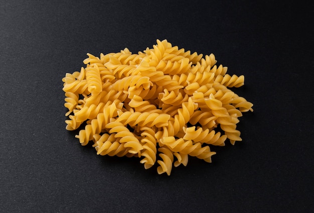 Pile of raw fusilli pasta isolated on black