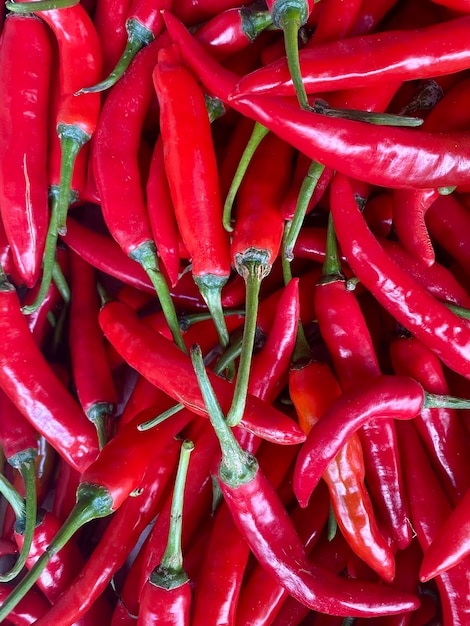 A pile of red chili peppers with green stems.