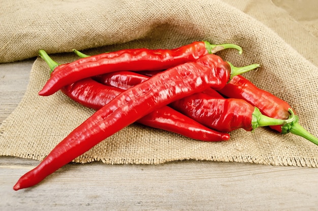 Pile of red sharp pepper on the background burlap and wooden planks