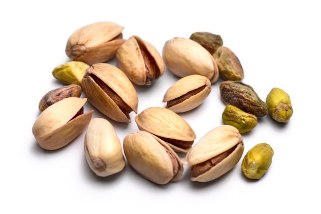 Pile of roasted pistachio nuts (Pistacia vera) isolated on white background