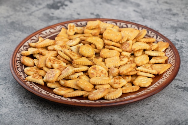 Pile of salted dry crackers placed on brown plate. 