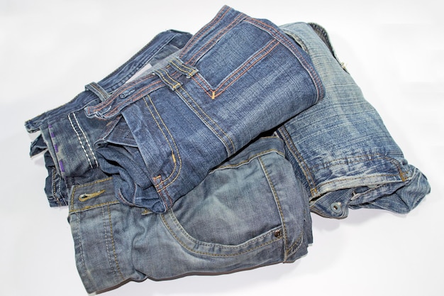 Pile of several blue jeans over white background