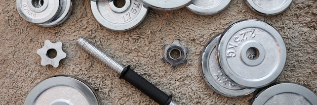 Pile of shiny chrome dumbbells disks lying around grip at home rug