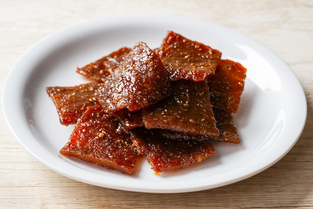 Pile of sliced pork jerky or bakkwa (Indonesian dendeng babi) styling on a white plate