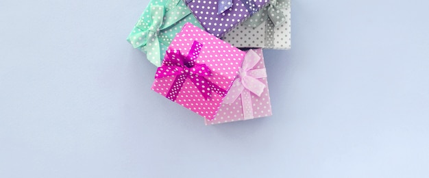 Pile of a small colored gift boxes with ribbons lies on a violet