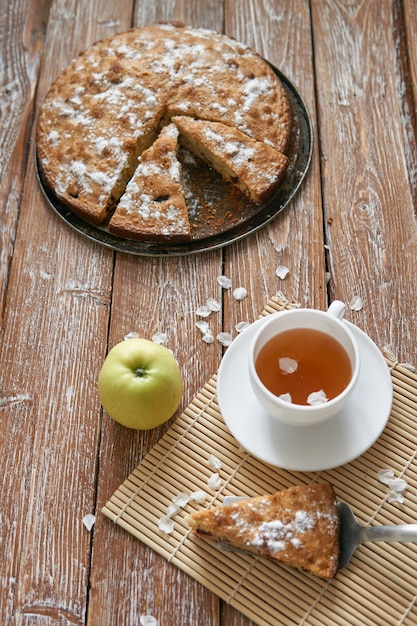 Mucchio di piccoli pancake fatti in casa con miele, tazza di tè e nido d'ape sul tavolo di legno