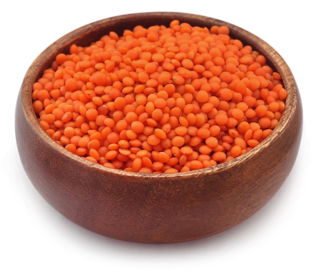 Pile of some fresh lentil in wooden bowl over white background