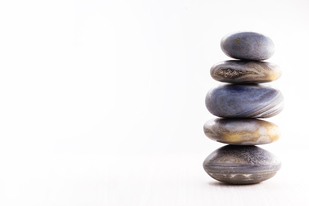 Pile of spa stones on the table against a white surface, copy space