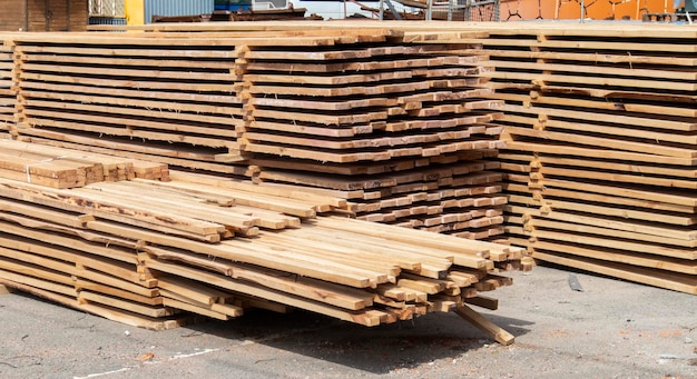 Pile of stacked wooden planks at a construction site Wooden boards lumber Industrial edged timber