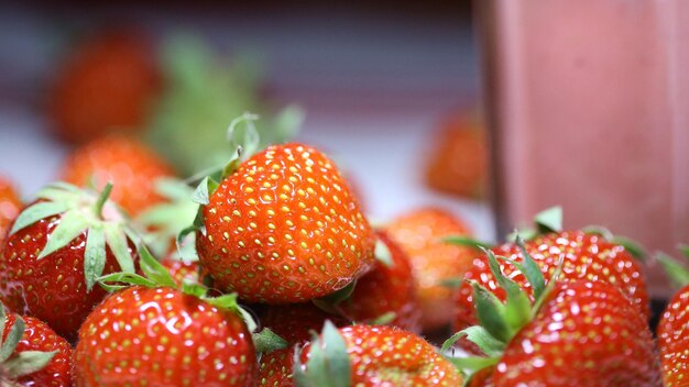 Photo a pile of strawberries with green leaves on them