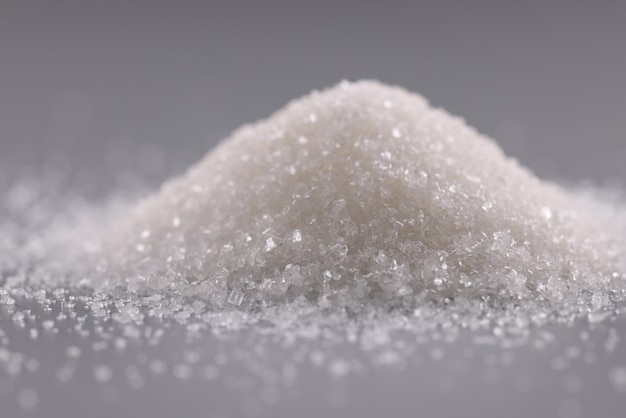 Pile of sugar crystals on grey surface heap of sweet powder to add in dishes