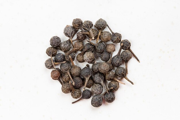 Pile of tailed pepper cubeb close up on gray