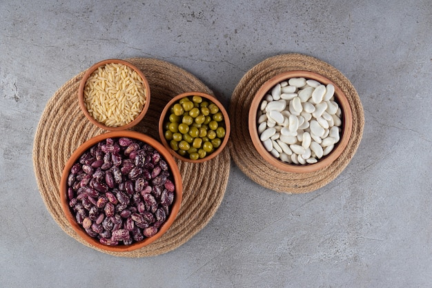 Pile of uncooked lentils, beans and rice on stone background. 