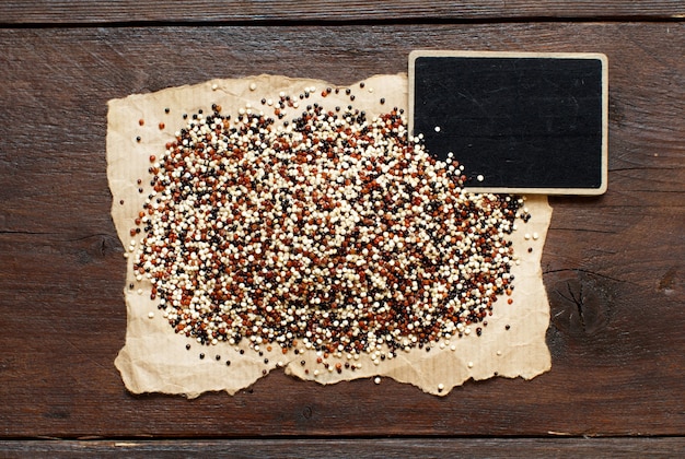 Pile of uncooked mixed red, white and black quinoa  with a  chalkboard