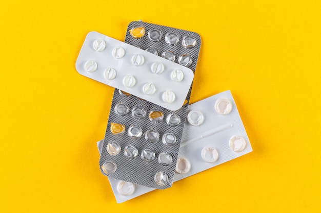 pile used blister packs of pills on yellow background