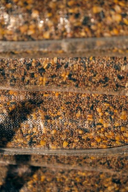 Pile of various animal feed grain mix in transparent bags arranged together in warehouse