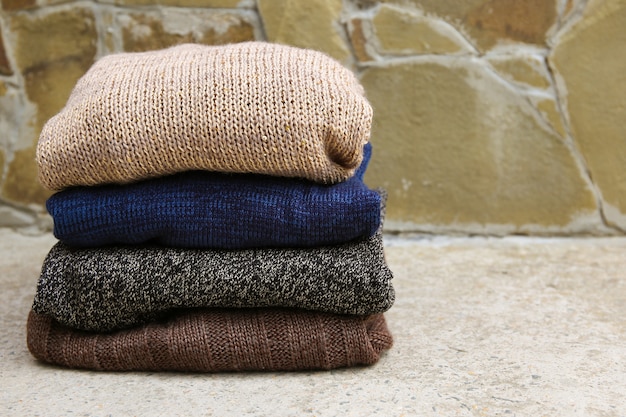 Pile of warm clothes on stone background.