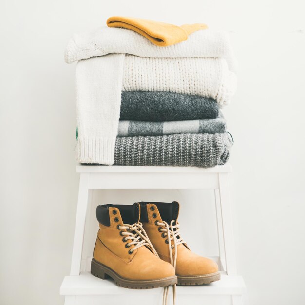 Pile of warm sweaters blankets cap and boots square crop
