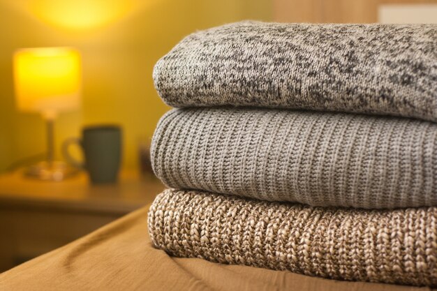 Куча теплых зимних осенних свитеров на кровати