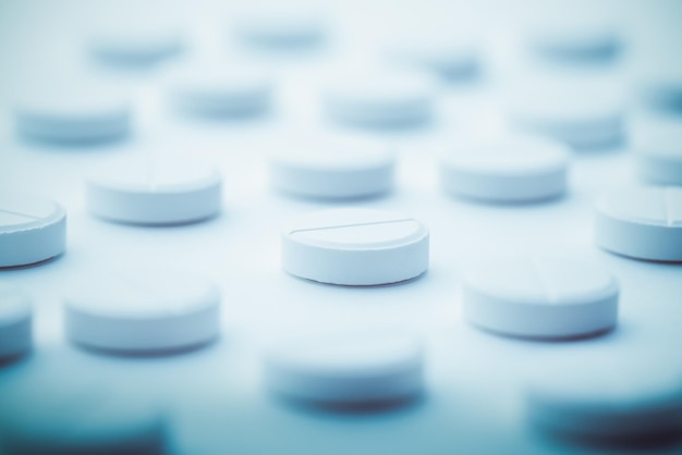 A pile of white pills scattered on a bright white background Selective focus Mockup layout