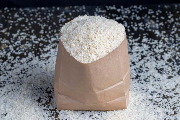 A pile of white rice in a paper bag and on the table