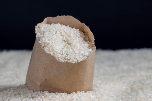 A pile of white rice in a paper bag and on the table